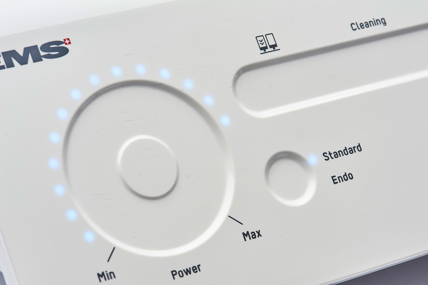 Nahaufnahme eines weißen zahnmedizinischen Geräts mit beleuchtetem Bedienfeld. Zu sehen sind Einstellmöglichkeiten wie ‚Power‘ von Min bis Max sowie die Modi ‚Standard‘ und ‚Endo‘. Nahaufnahme eines weißen zahnmedizinischen Geräts mit beleuchtetem Bedienfeld. Zu sehen sind Einstellmöglichkeiten wie ‚Power‘ von Min bis Max sowie die Modi ‚Standard‘ und ‚Endo‘.
